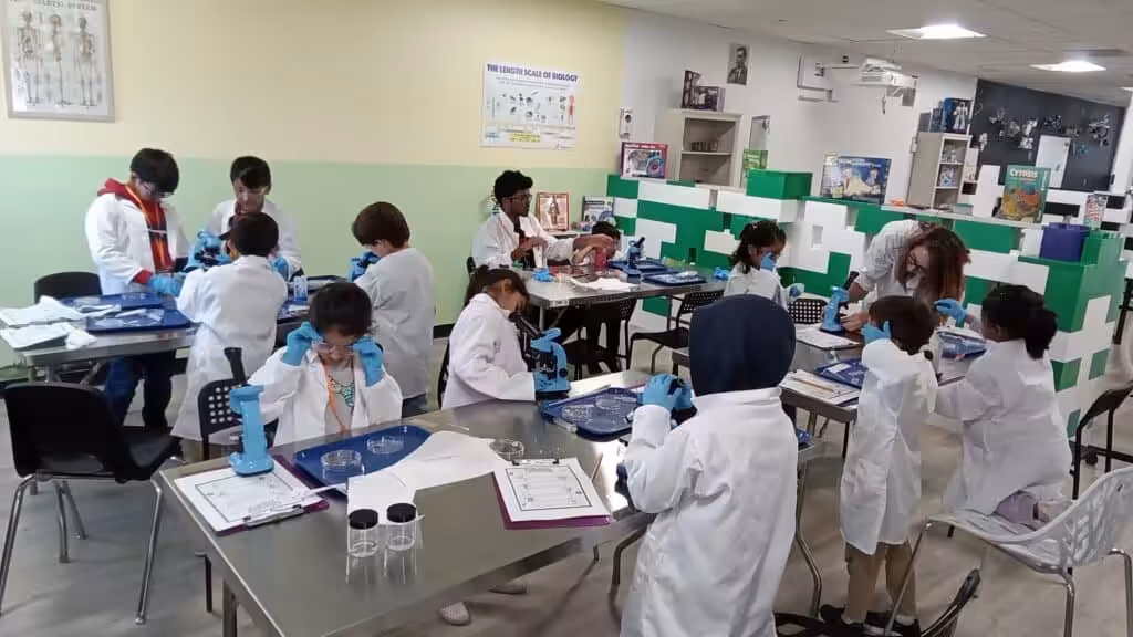 Students conducting science experiments in a classroom lab with microscopes.