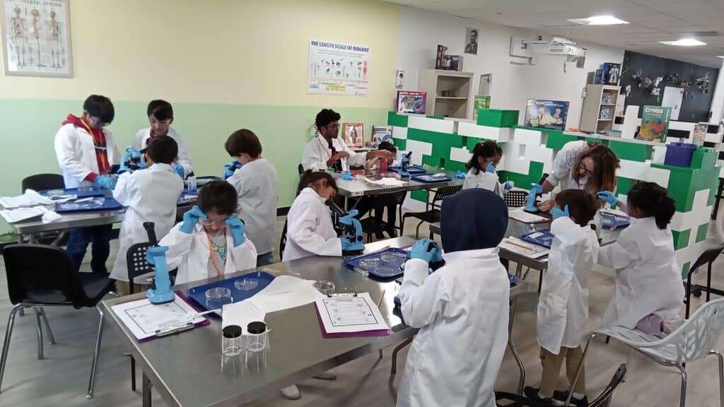 Students conducting science experiments in a classroom lab with microscopes.